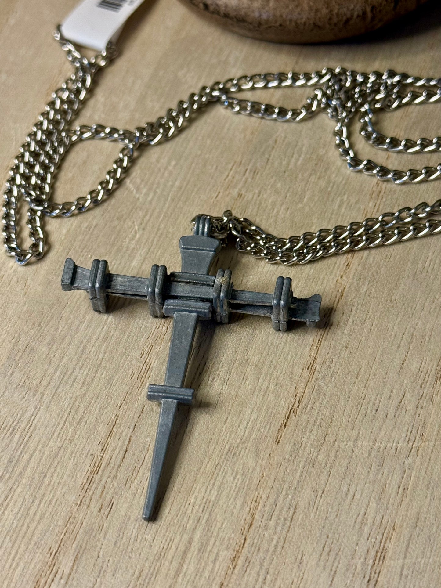 Necklace with a metal cross pendant on a wooden surface