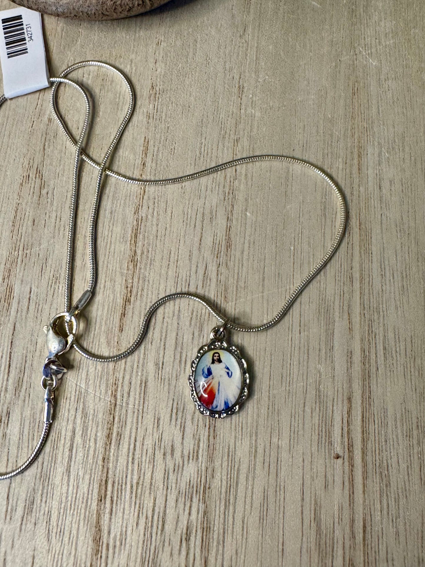 Necklace with a pendant featuring an image of a religious figure on a wooden surface