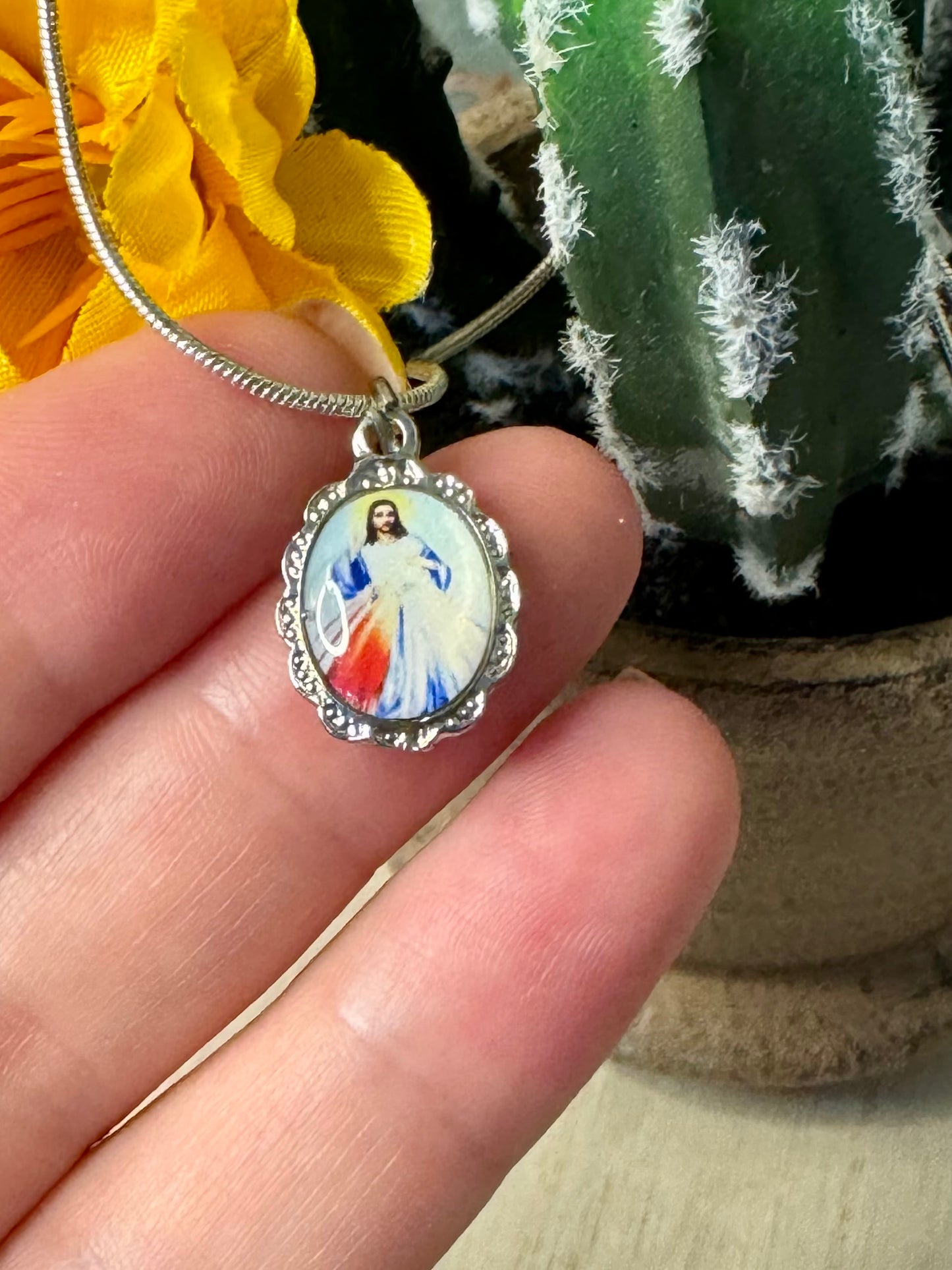 Pendant with religious design held by a hand, with a blurred background
