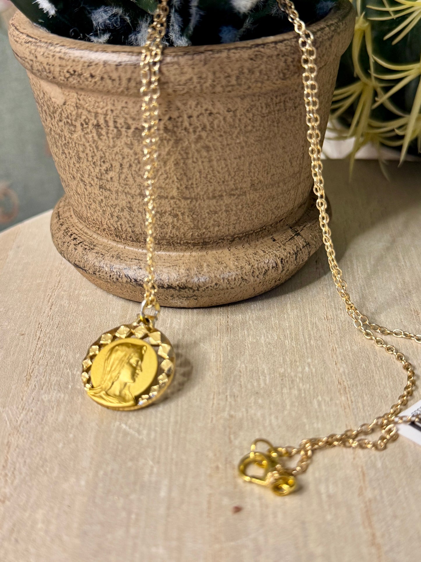 Gold necklace with a round pendant on a textured surface