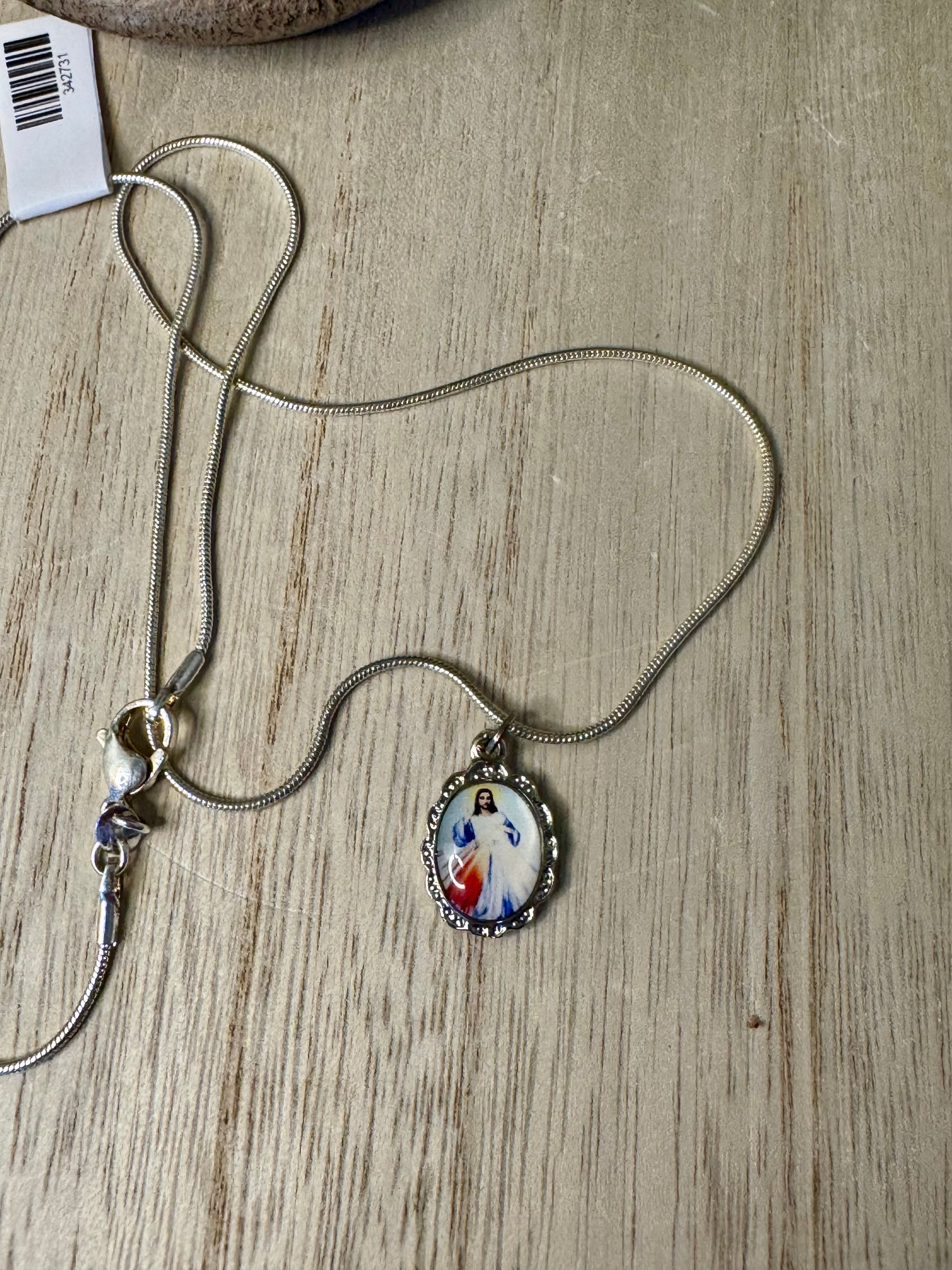 Necklace with a pendant featuring an image of a religious figure on a wooden surface