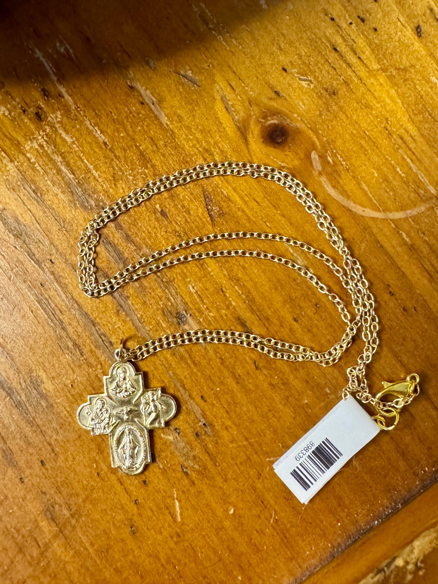 Gold necklace with a cross pendant on a wooden surface