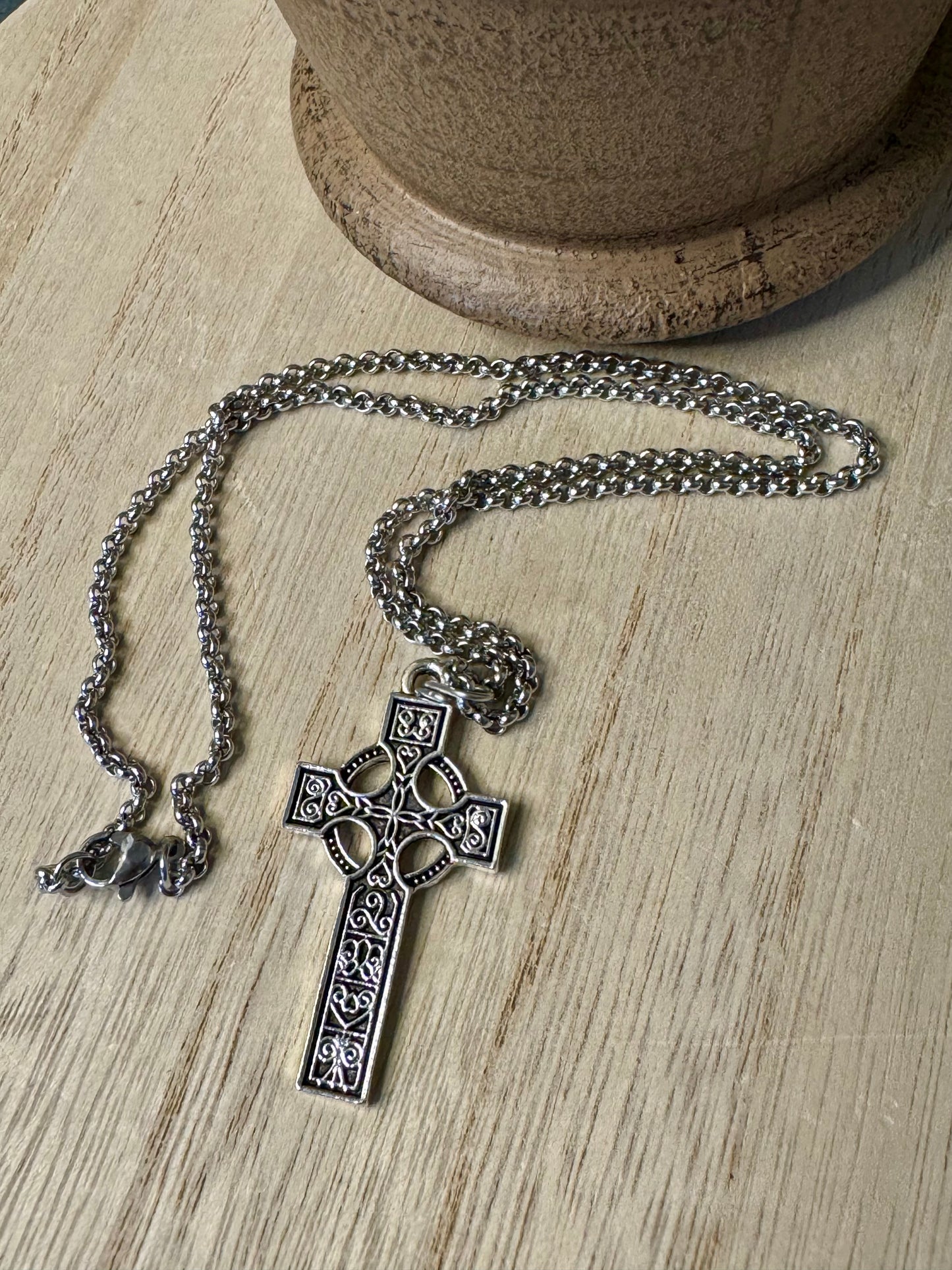 Silver cross necklace on a wooden surface