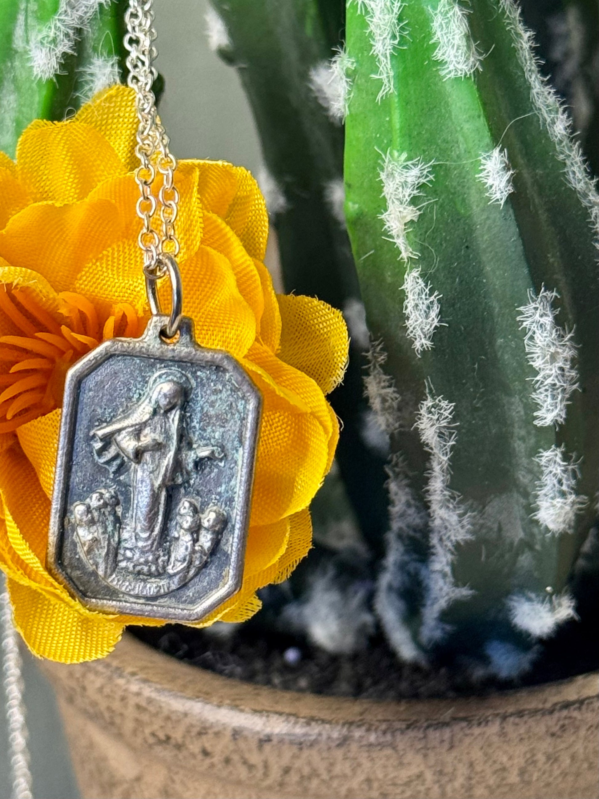 Silver pendant on a yellow flower with a cactus in the background