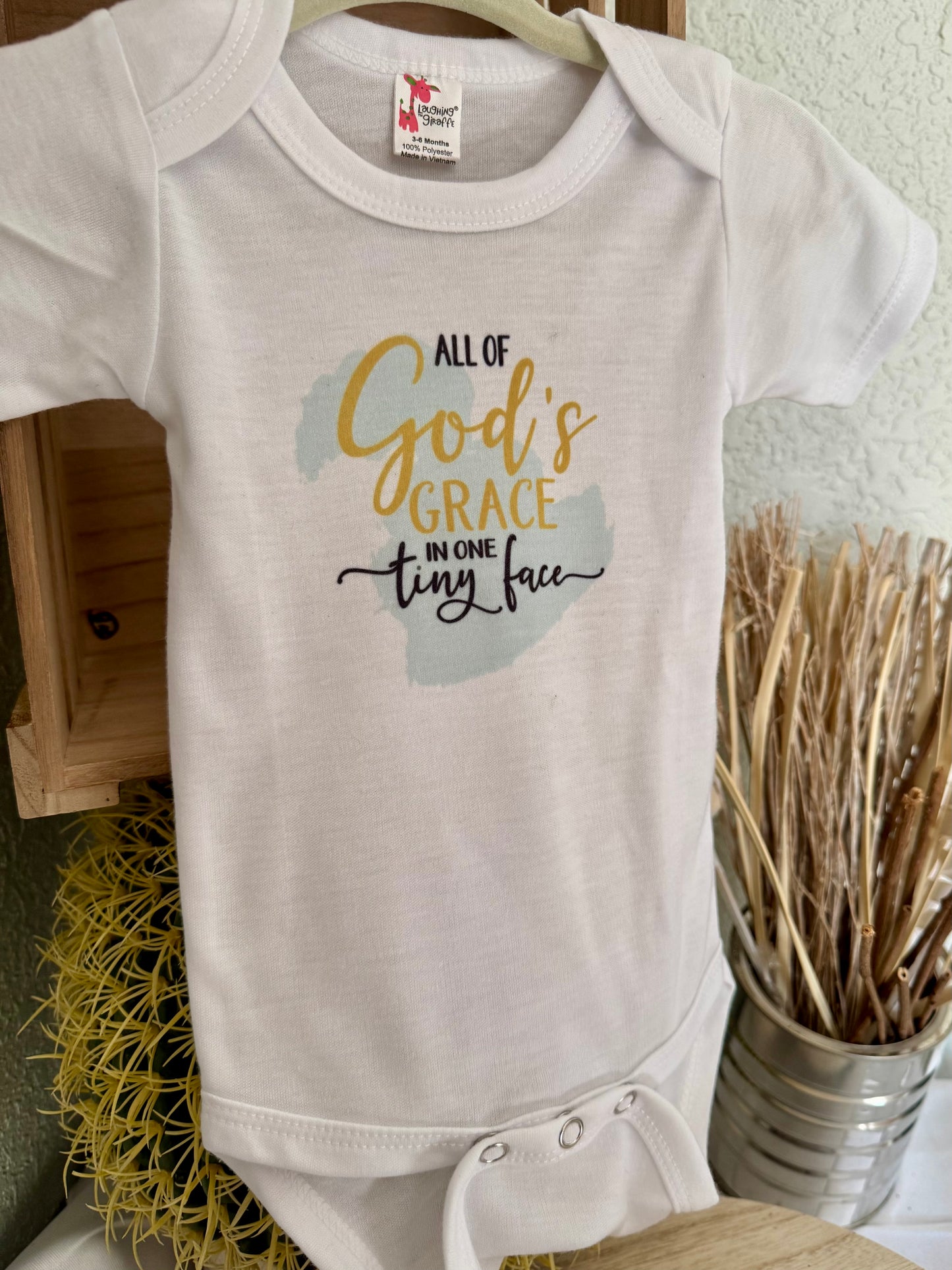 All God’s Grace in One Tiny Face Baby Onesie