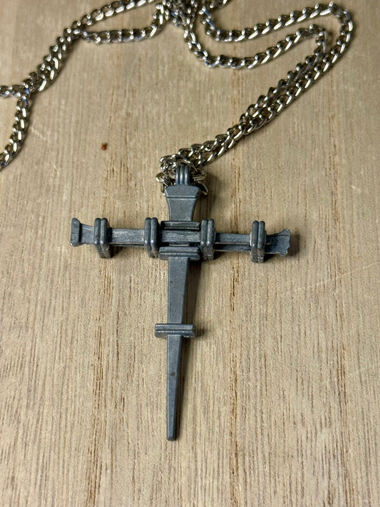 Metallic cross pendant on a chain against a wooden background