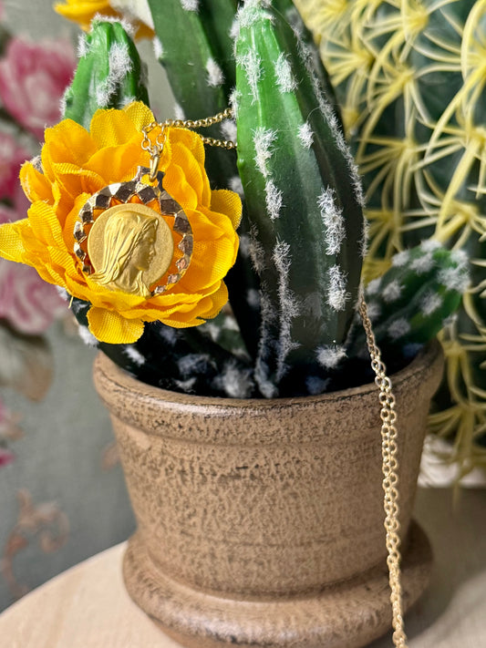 Decorative necklace with a yellow flower pendant on a cactus plant.