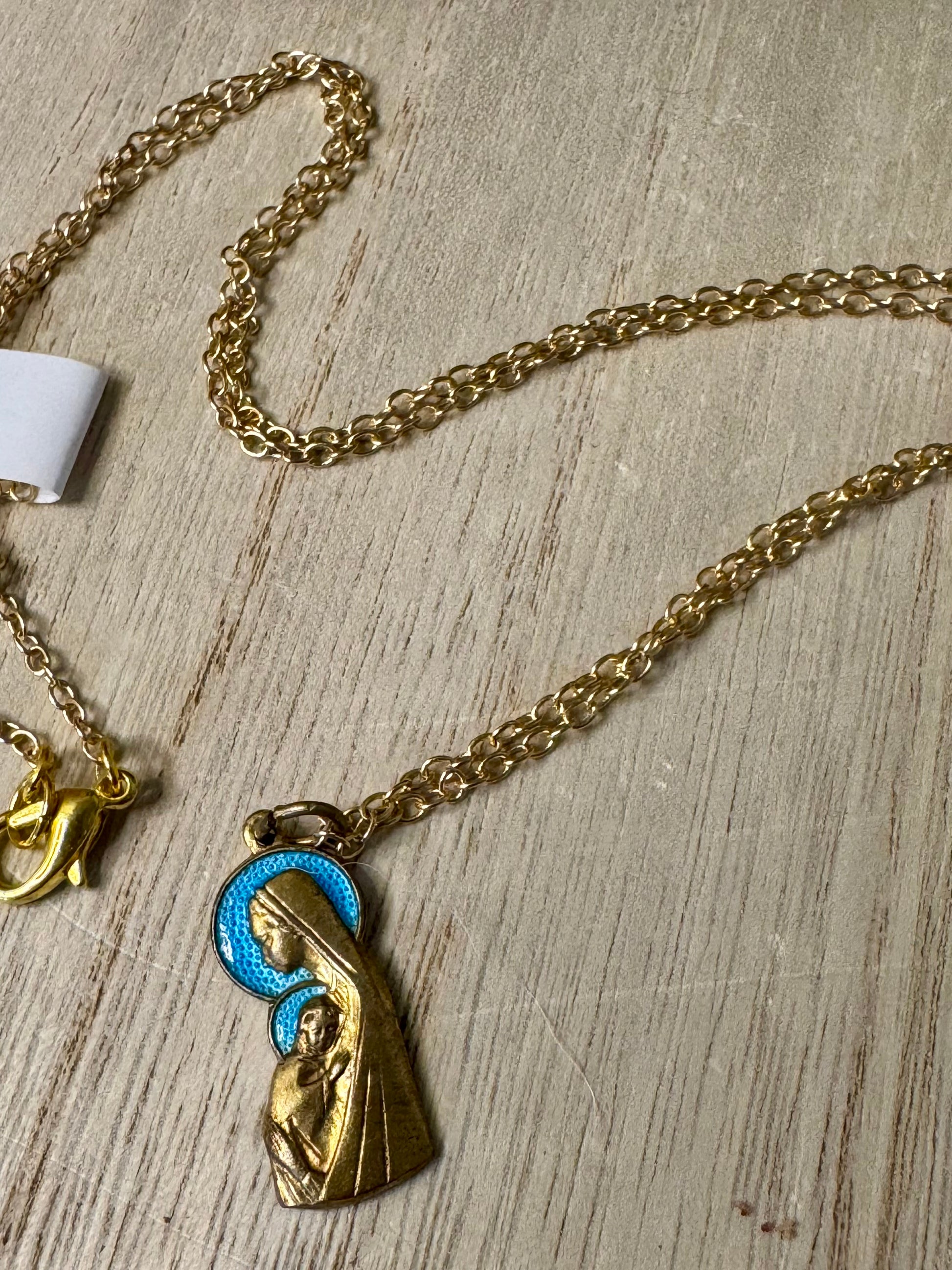 Gold necklace with a religious pendant on a wooden surface