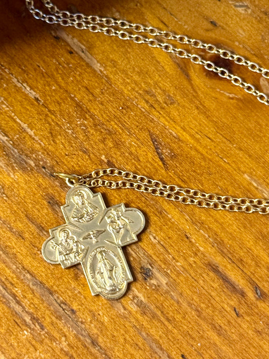 Gold cross pendant necklace on a wooden surface