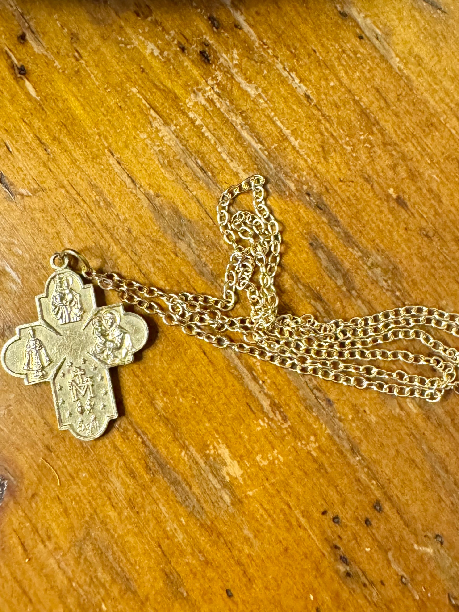 Gold cross pendant necklace on a wooden surface