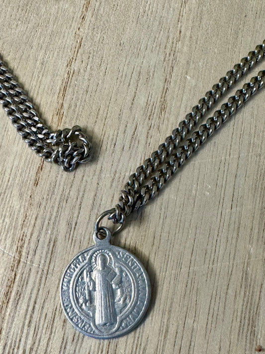 Silver chain necklace with a medallion on a wooden surface