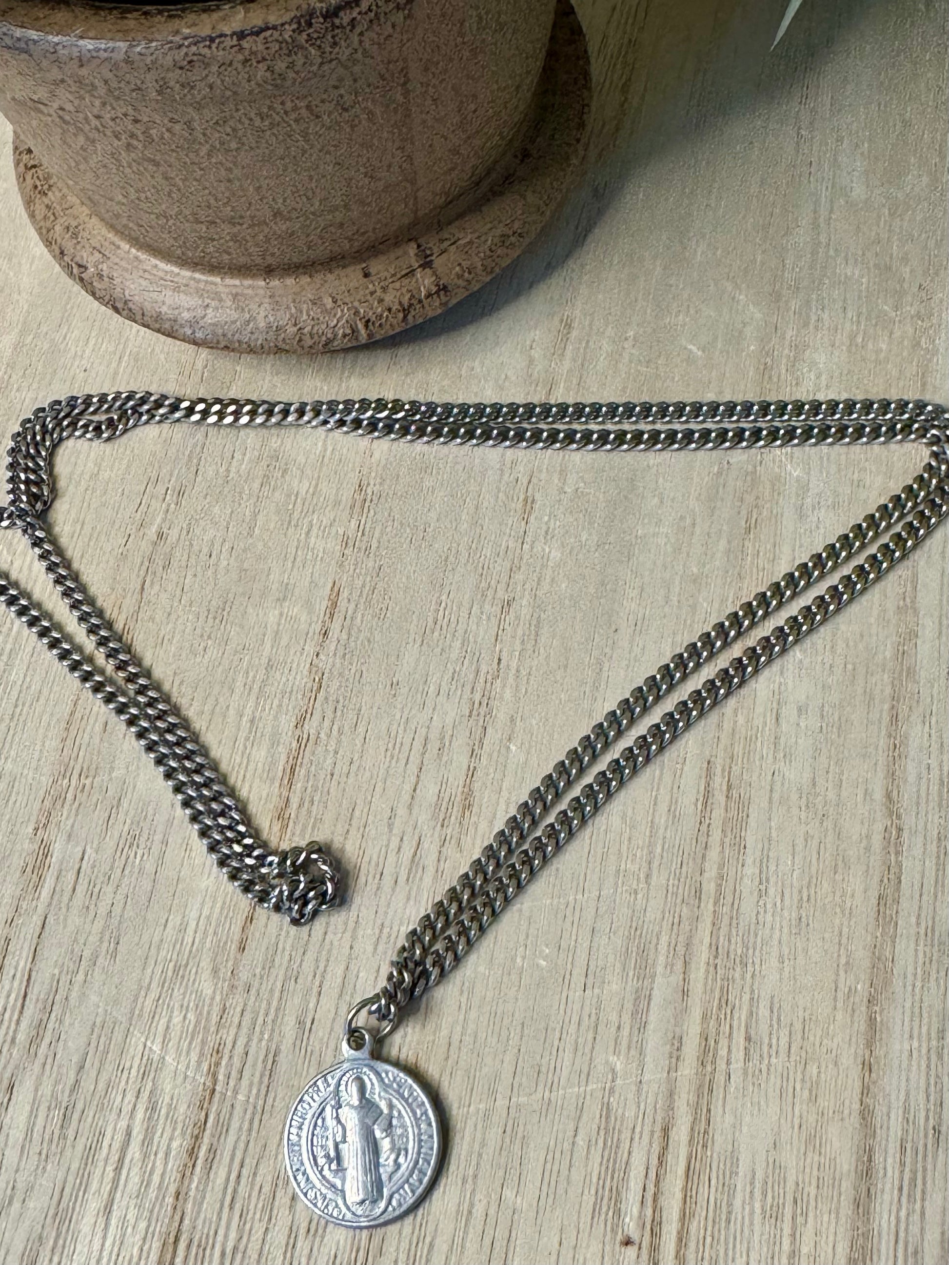 Silver chain necklace with a pendant on a wooden surface