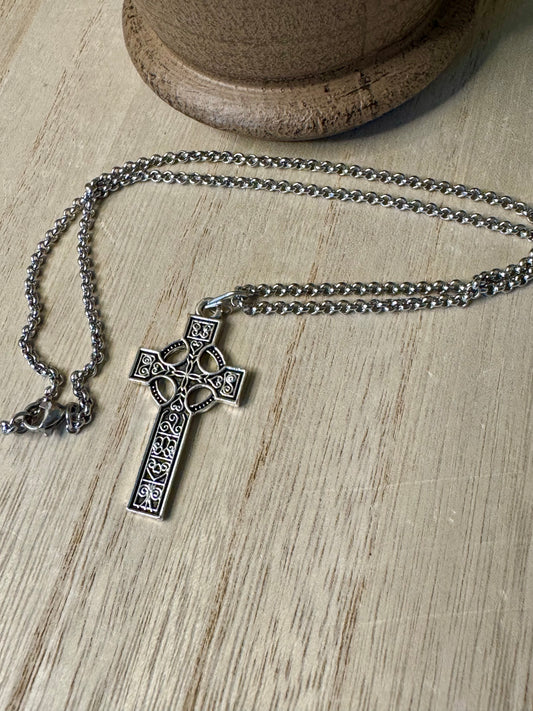 Silver cross necklace on a wooden surface