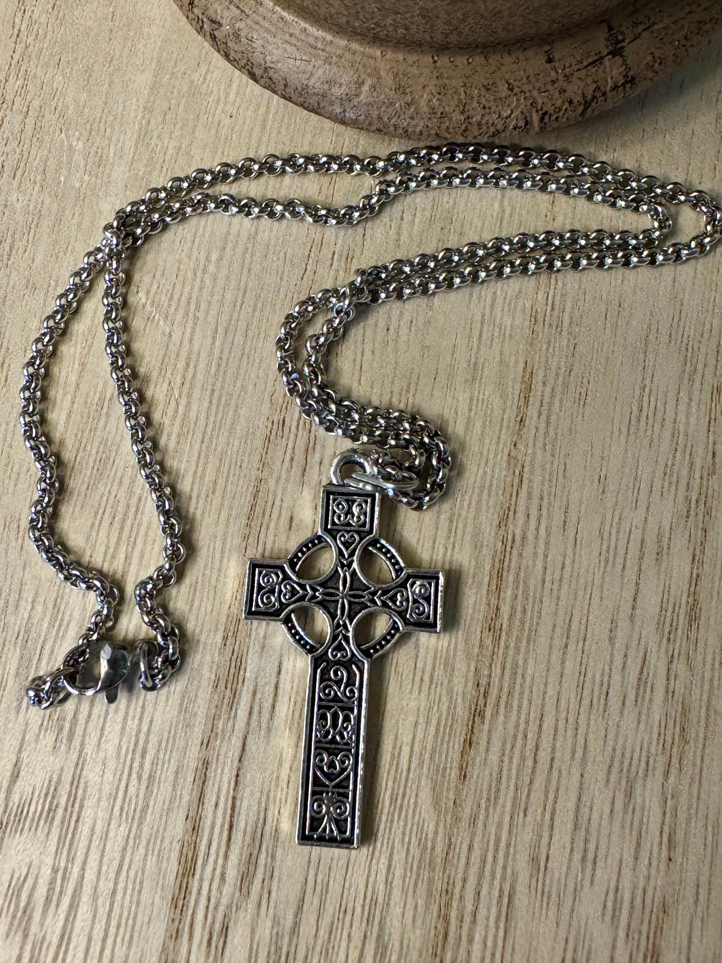 Silver cross necklace on a wooden surface