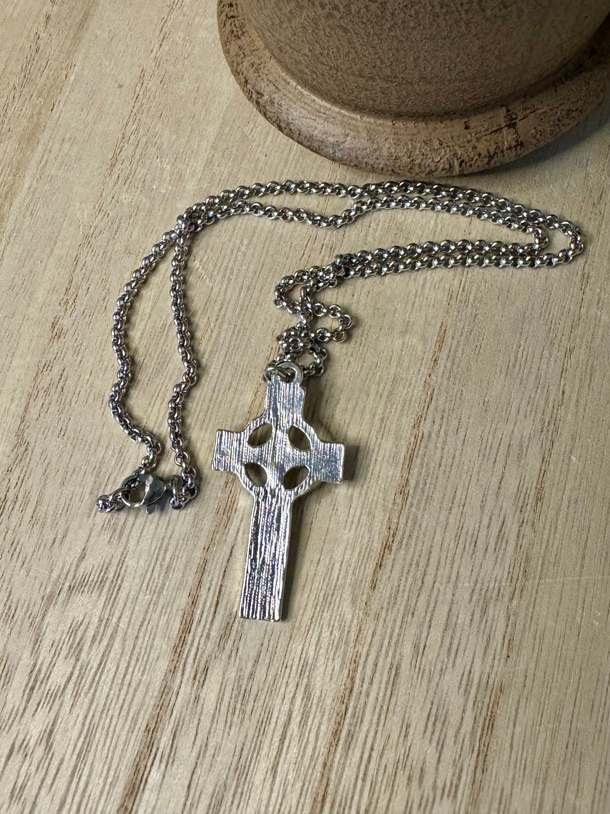 Silver cross necklace on a wooden surface