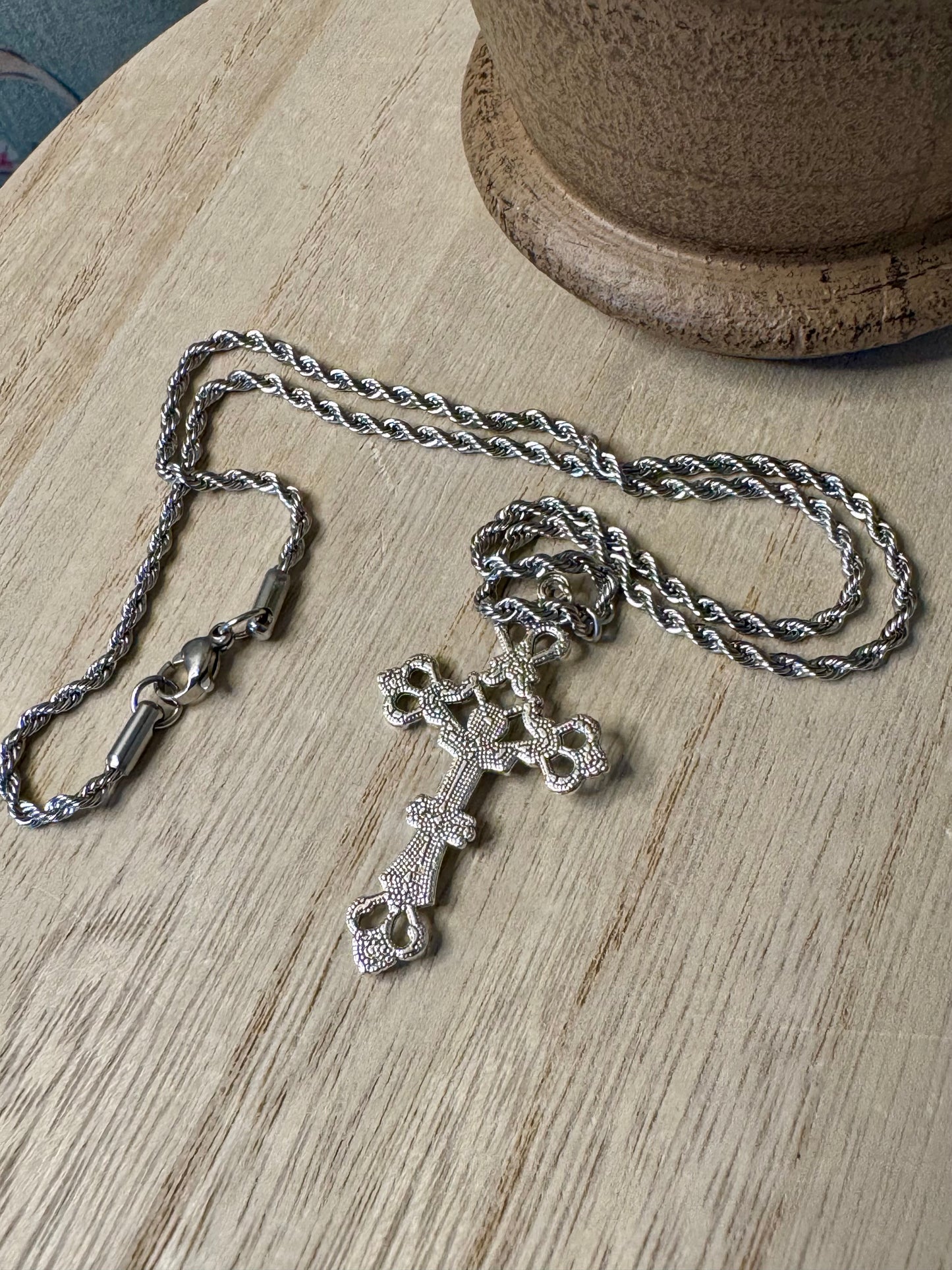 Silver necklace with a cross pendant on a wooden surface