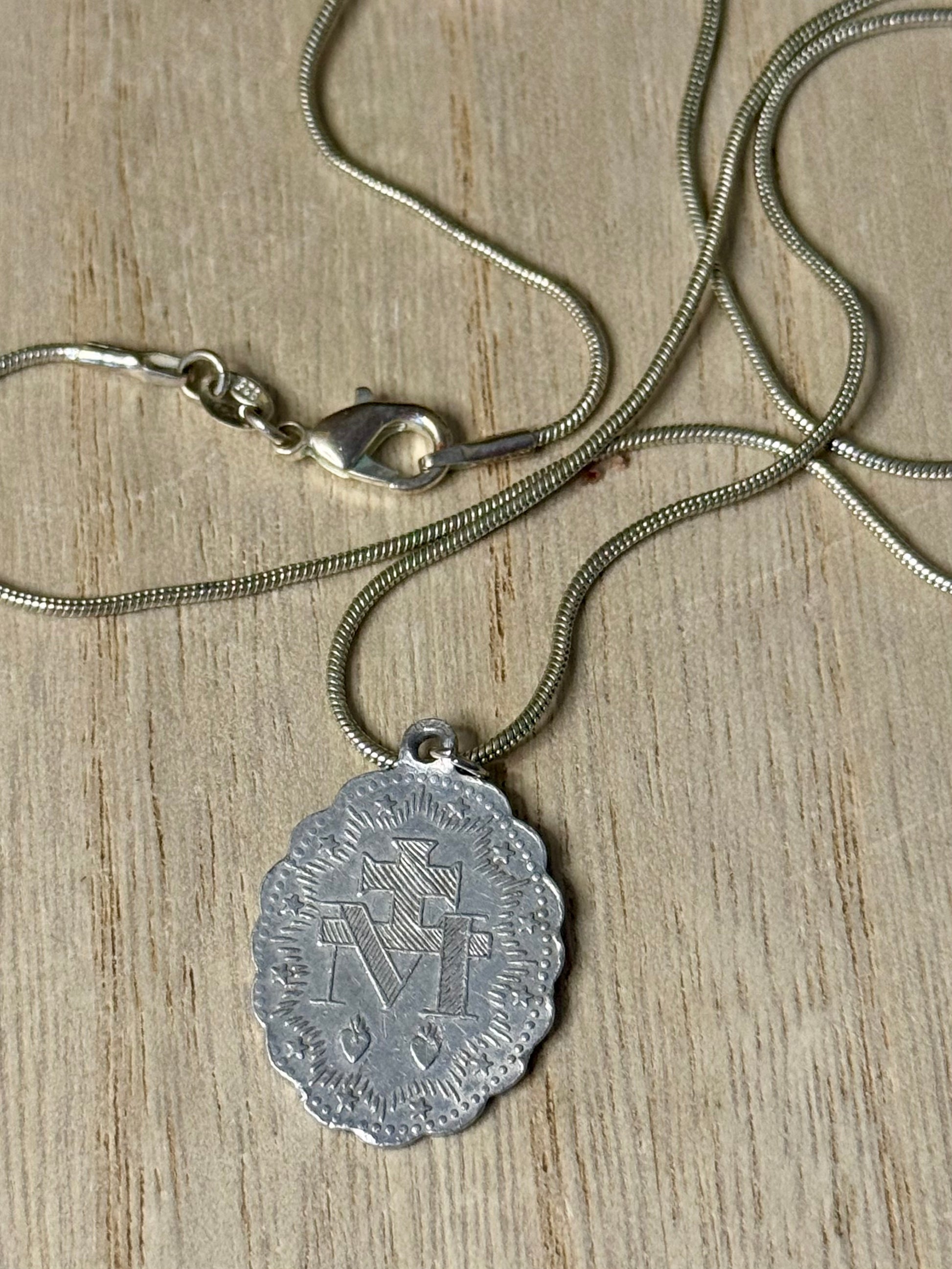 Silver necklace with a pendant on a wooden surface